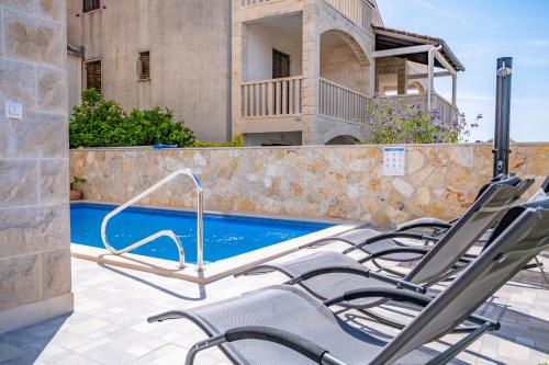 un grupo de sillas sentadas junto a una piscina en Luxury apartment "Blue Diamond", en Postira