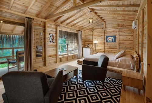 a log cabin bedroom with a bed and chairs at Flavia Hotel in Kızılcakaya