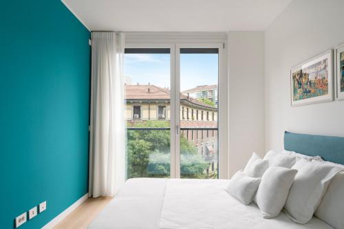 a white and blue bedroom with a large window at Tolomeo in Milan