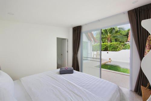 a bedroom with a white bed and a large window at Villa Lawana - Bophut - Stylish Private Luxury Villa in Bophut