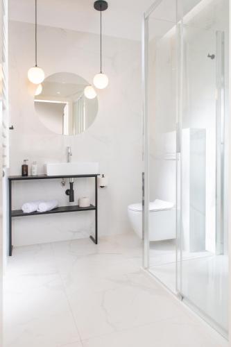 a white bathroom with a sink and a shower at Rajska Residence in Krakow