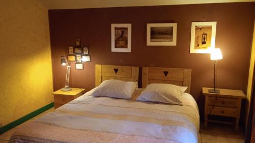 a bedroom with a bed with two lamps and pictures on the wall at Le Mas Franc in Enveitg