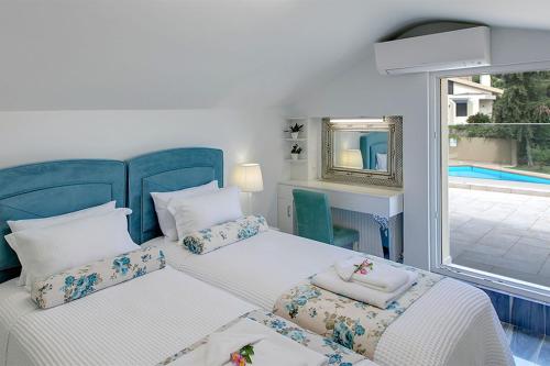 1 dormitorio con 2 camas y vistas a la piscina en Azalea Villa Sani, Sani Luxury Villas Collection en Sani Beach