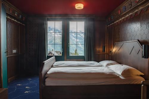 Schlafzimmer mit einem großen Bett und einem Fenster in der Unterkunft Hotel Drei Berge in Mürren