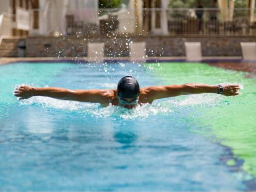 Ein Mann, der in einem Pool mit ausgestreckten Armen schwimmt. in der Unterkunft Kairos Valley Health & Nature Resort in Datca