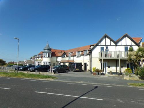 a large white building with cars parked in a parking lot at 3TheDome - Luxury Ground Floor Apartment opposite the Beach, Barton on Sea in Barton on Sea