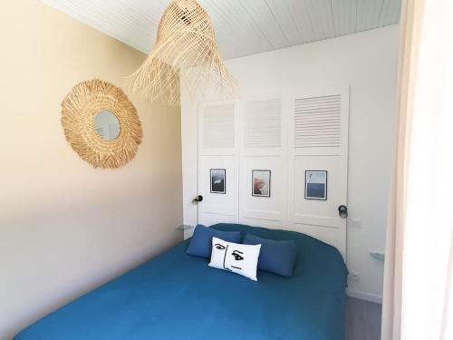 une chambre avec un lit bleu et un miroir dans l'établissement La Maraîchine Ensoleillée, à Saint-Jean-de-Monts