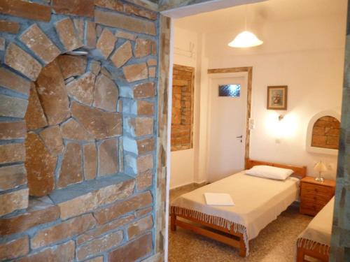 Un dormitorio con una pared de piedra y una cama. en Vasilis Place Ιos, en Ios Chora