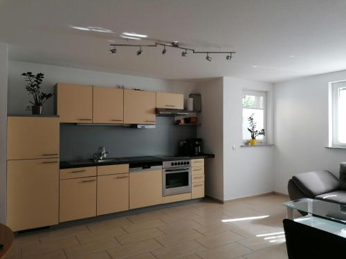 eine Küche mit braunen Schränken und einer Couch in einem Zimmer in der Unterkunft Ferienwohnung Weingut Brutscher in Roschbach