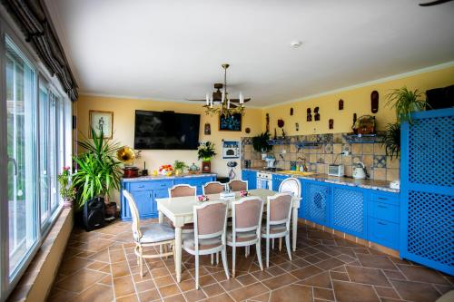 a kitchen with blue cabinets and a table and chairs at Къща за гости Кала in Patalenitsa