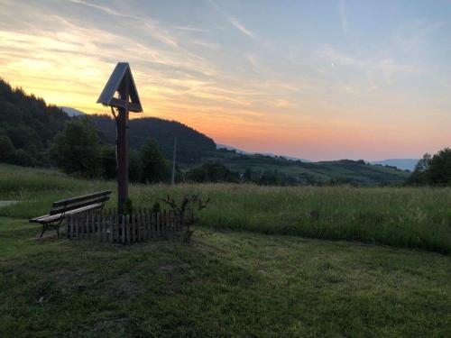 a bench sitting in a field with a sign at Dom pod Matyską in Radziechowy