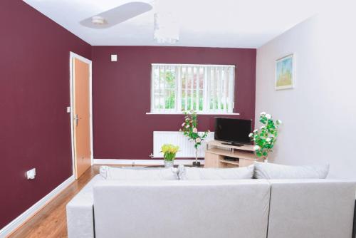 a living room with a white couch and a purple wall at 87 Rawsthorne Avenue in Manchester