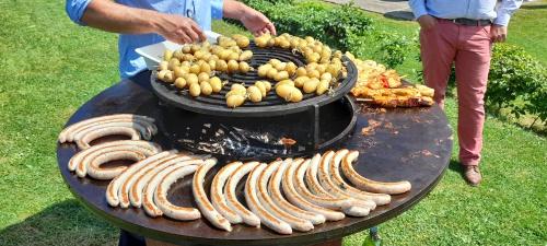 a man cooking a bunch of hot dogs on a grill at La Cense de Baudecet in Gembloux