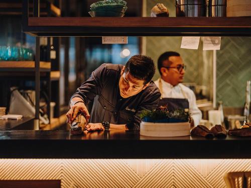 a chef preparing food at a counter in a restaurant at Aguas de Ibiza Grand Luxe Hotel - Small Luxury Hotel of the World in Santa Eularia des Riu