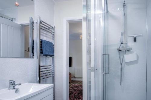 a white bathroom with a shower and a sink at Croft Court - 1 Bedroom Apartment - Tenby in Tenby