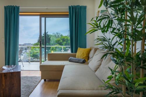 a living room with a couch and a large plant at Sesimbra Prime Apartment by be@home in Sesimbra