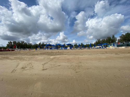 Maronda Camping في مارينا دي مونتينيرو: شاطئ فيه كراسي ومظلات في يوم غائم