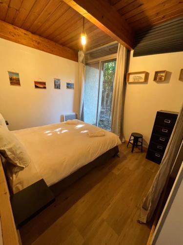 sypialnia z dużym łóżkiem i oknem w obiekcie Barcelonnette location avec jardin w mieście Barcelonnette