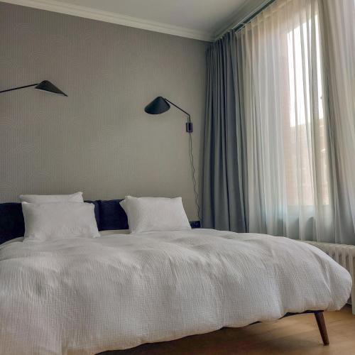 a bedroom with a white bed with two lamps and a window at Boutique Hotel Marie Marie in Dendermonde