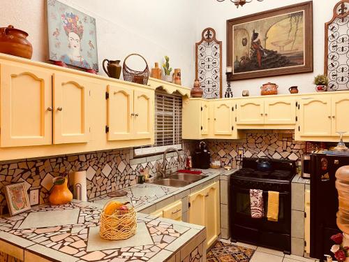 a kitchen with yellow cabinets and a stove top oven at Cozy Apartment Villas in Rosarito