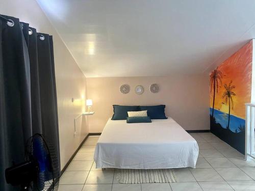 1 dormitorio con 1 cama y una pintura en la pared en Fish Lodge en Paea