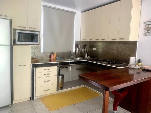 a kitchen with white cabinets and a wooden table at Fish Lodge in Paea