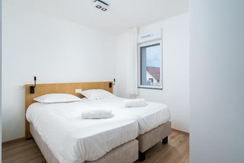 a bedroom with a large bed with white sheets and a window at Evancy Equihen-Plage in Équihen-Plage