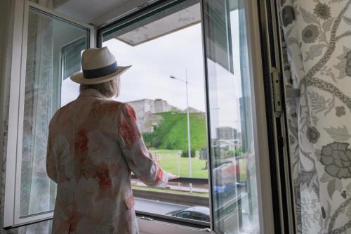a woman in a hat looking out of a window at Supernova in Savona