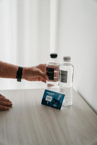 a person holding two bottles of water on a table at Hotel Villa Sorriso in Lido di Jesolo