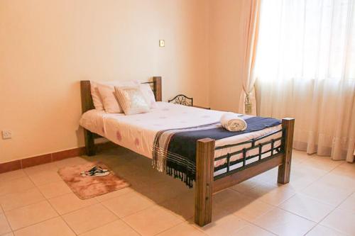 a bed sitting in a room with a window at Windy Ridge Karen View Palace Apartment in Nairobi