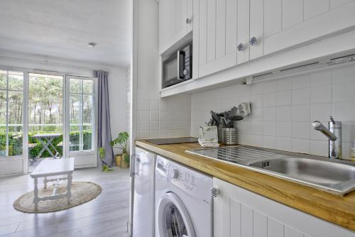 une cuisine avec un évier et une machine à laver dans l'établissement Appartement rénové et cosy dans résidence vacances, à Lacanau-Océan