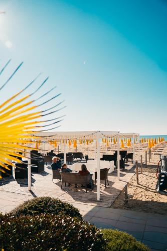 a beach with umbrellas and people sitting on benches at Hotel Villa Sorriso in Lido di Jesolo