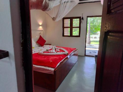 a bedroom with a bed with a red blanket at Kilimani Kwetu Beach Hotel in Bwejuu