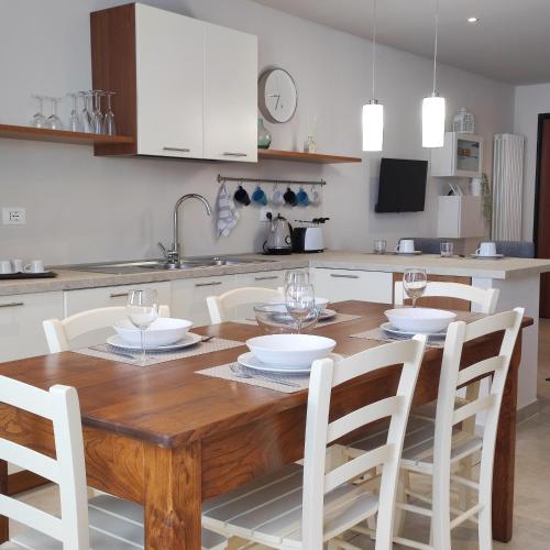 a kitchen with a wooden table and white chairs at Casa Italo in Gardone Riviera