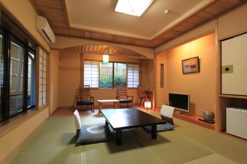 sala de estar con mesa, sillas y TV en Yusakaso, en Hakone