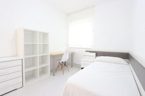 a white bedroom with a bed and a desk at Apartamento BELLAS VISTAS in Béjar