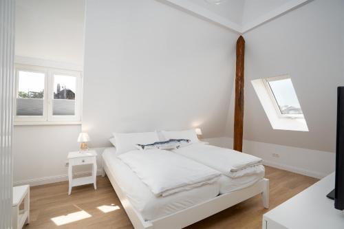 ein weißes Schlafzimmer mit einem Bett und zwei Fenstern in der Unterkunft KUR18 Ferienwohnung Baltic Deck in Timmendorfer Strand