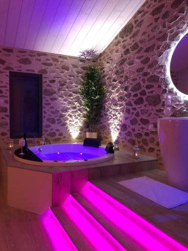 a bathroom with a hot tub with pink lighting at L’idîle in LʼÉpine
