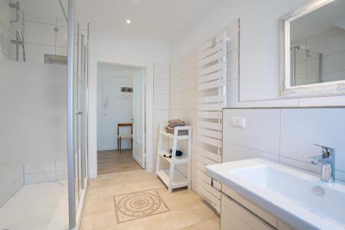 een witte badkamer met een wastafel en een spiegel bij KUR18 Ferienwohnung Baltic Deck in Timmendorfer Strand