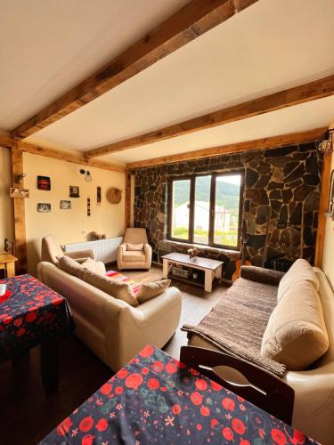 a living room with couches and a stone wall at Ioska's House in Mestia