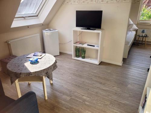 a living room with a small table and a television at Pension Lotsenhaus in Greetsiel
