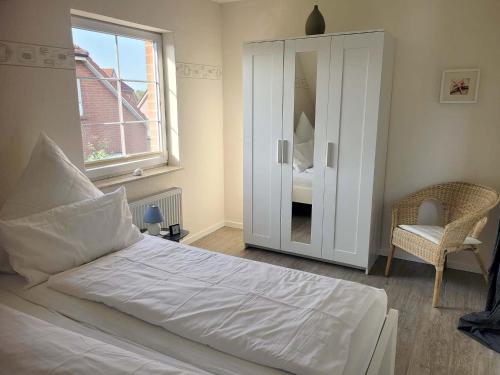 Un dormitorio con una gran cama blanca y una ventana en Pension Lotsenhaus, en Greetsiel