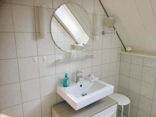 a white bathroom with a sink and a mirror at Pension Lotsenhaus in Greetsiel