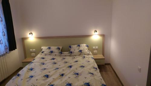 a bedroom with a bed with blue flowers on it at Eva's Little House - Acasă la Tăticul Albinelor in Şinca Veche