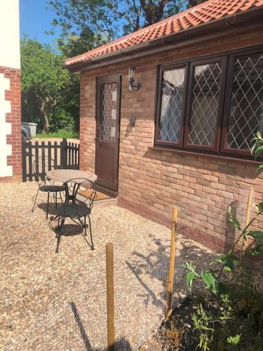 a small brick building with a table and a patio at Ash Cottage in Skegness