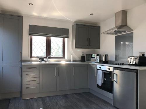 a kitchen with gray cabinets and a stove top oven at Ash Cottage in Skegness