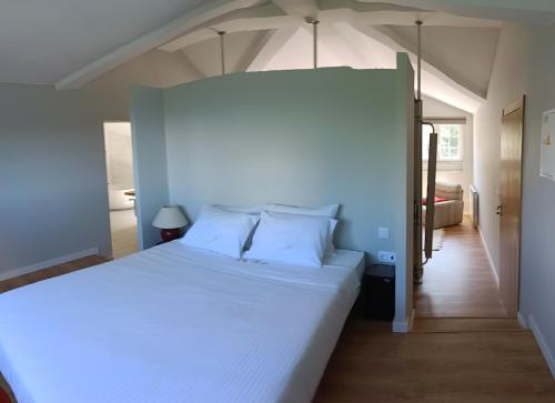 um quarto com uma grande cama branca num quarto em Quinta de Marzovelos em Viseu