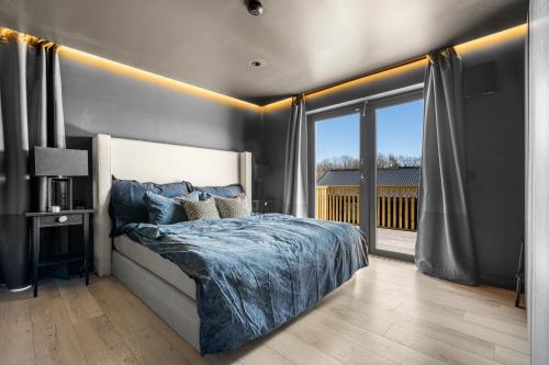 een slaapkamer met een bed en een groot raam bij Nytt og sjønært hus med boblebad til leie! in Grimstad