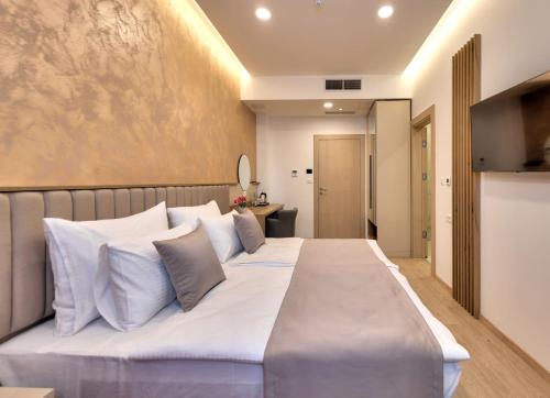 1 dormitorio con 1 cama grande con almohadas blancas en Hotel Emerald, en Mostar