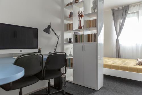 een slaapkamer met een bureau met 2 stoelen en een computermonitor bij Apartman Pletisanak in Gornji Milanovac